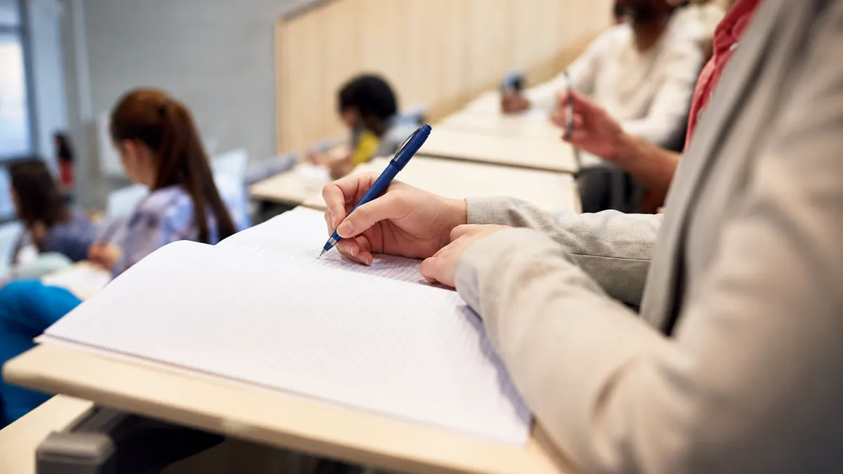 Étudiante prenant des notes dans un amphithéâtre pendant un examen