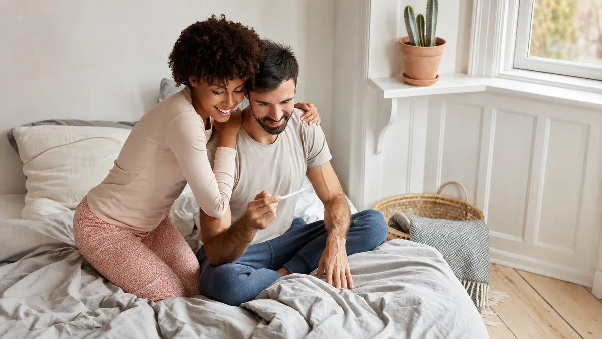 Couple souriant découvrant un test de grossesse positif