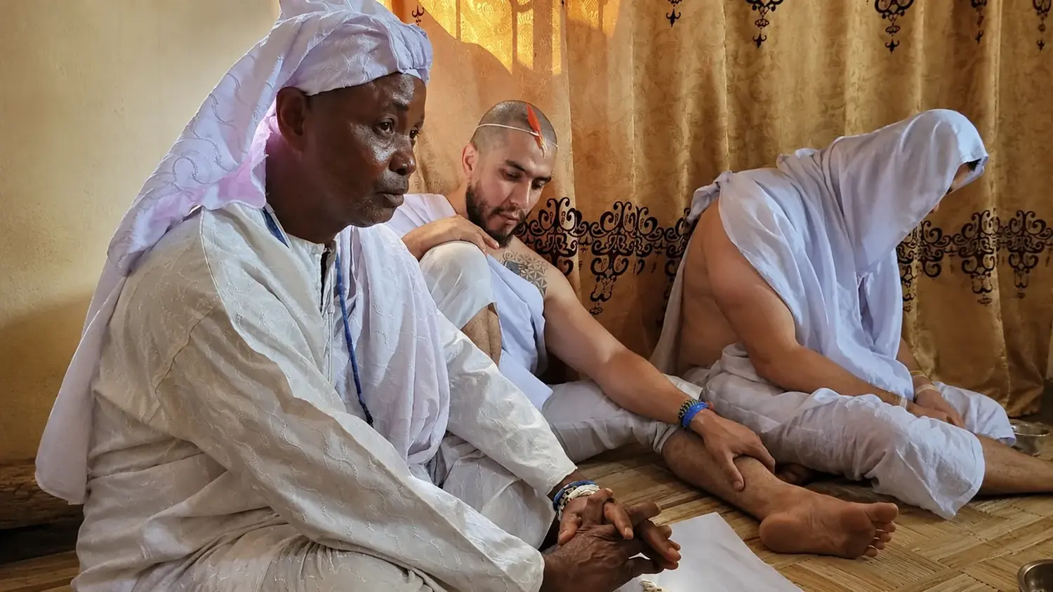 Maître Abila en cérémonie traditionnelle, aux côtés d'un consultant vêtu de blanc