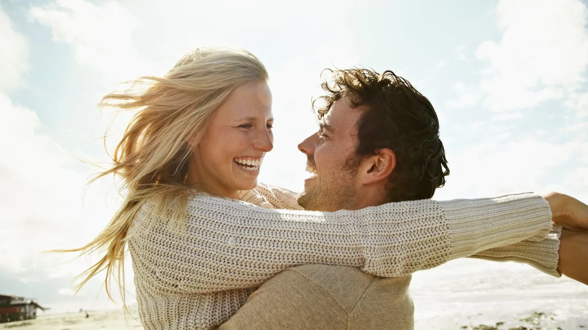 Couple enlacé et souriant sur une plage ensoleillée après un retour affectif